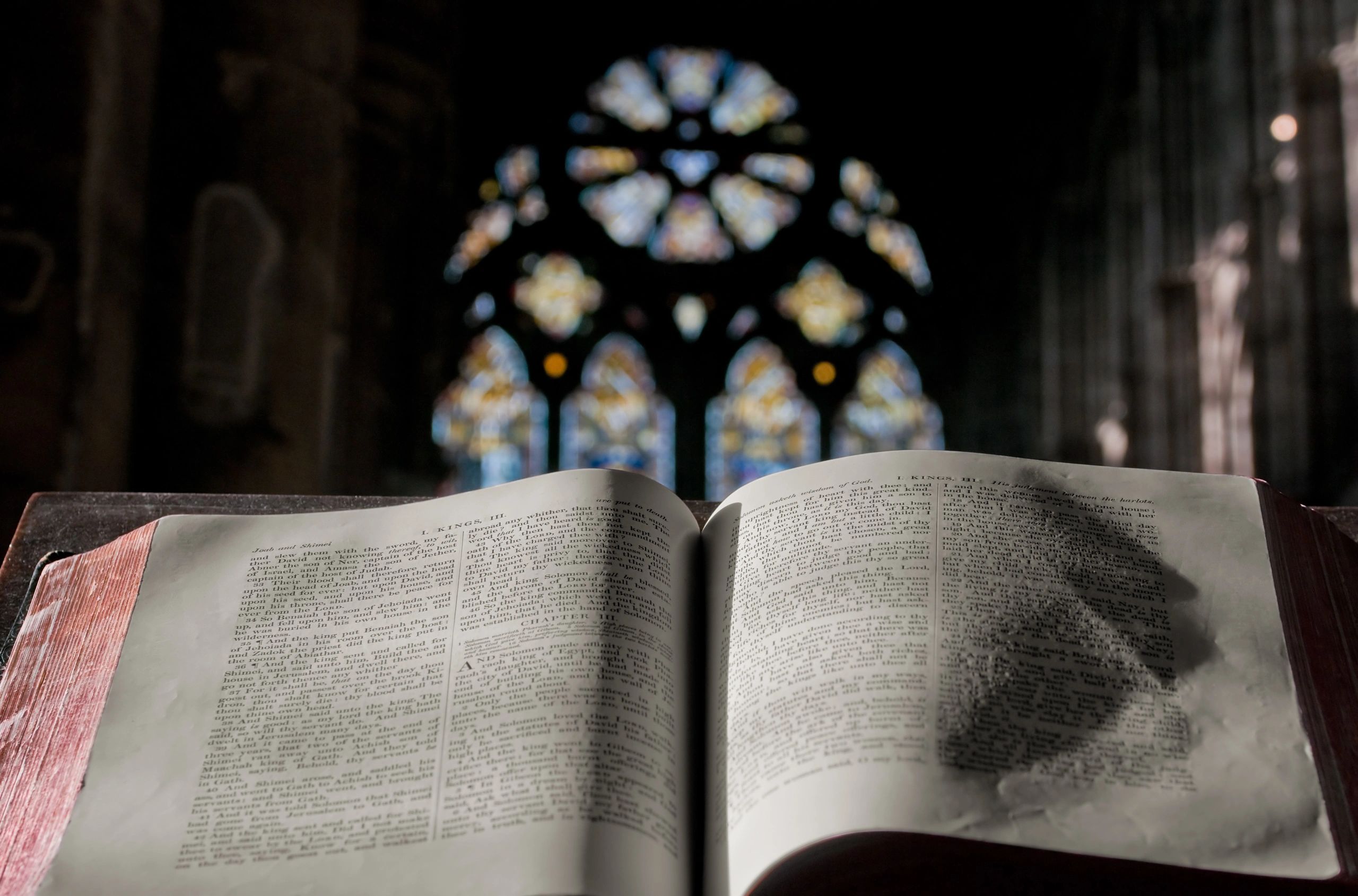 Open Bible in front of a stained glass window